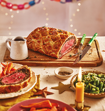 Sliced beef wellington in golden lattice pastry on a serving platter
